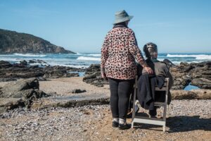 Two senior women enjoying a peaceful moment by the rocky beach, embracing friendship and serenity.