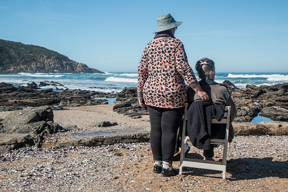 Two senior women enjoying a peaceful moment by the rocky beach, embracing friendship and serenity.